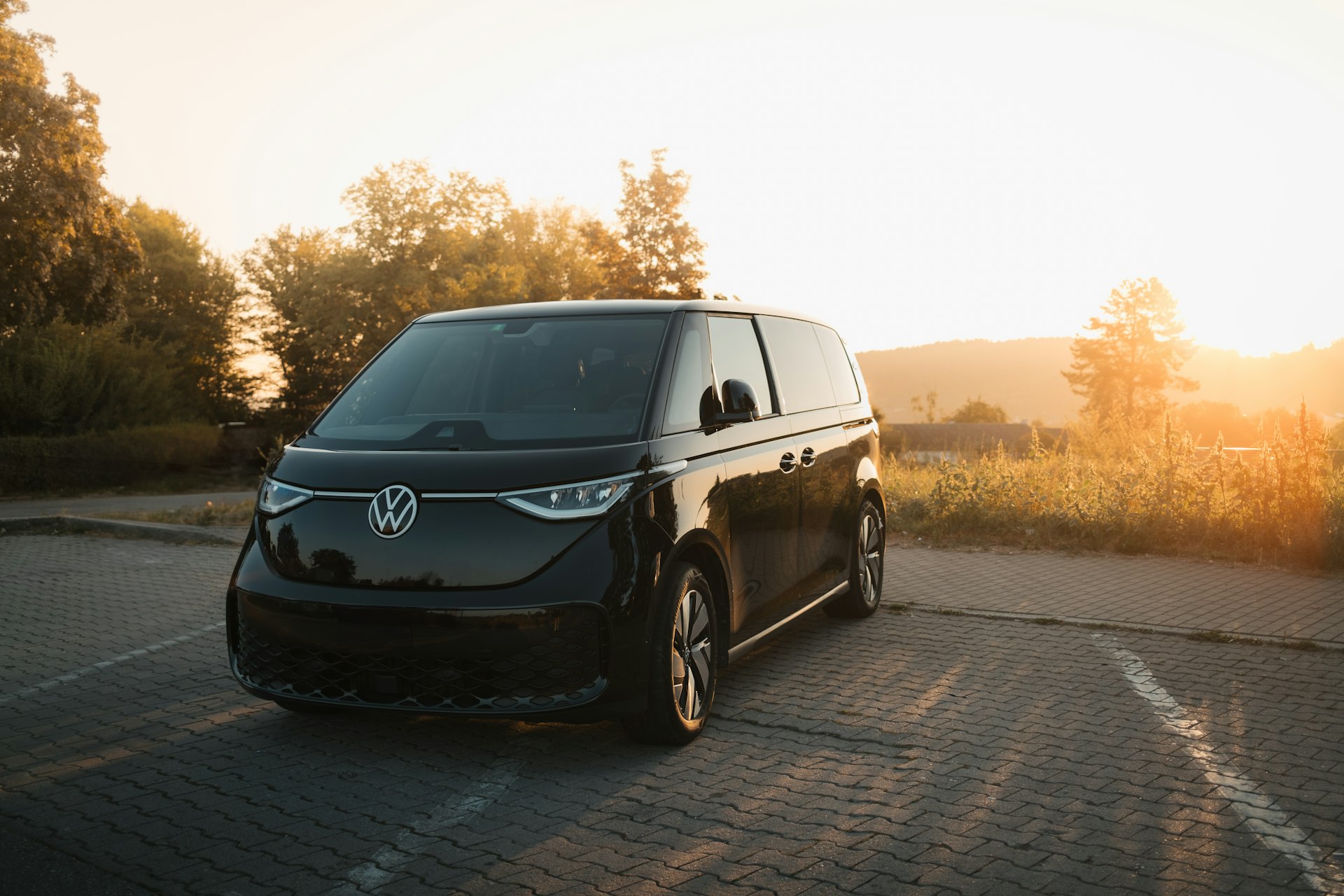 A black van driving down a road next to a forest